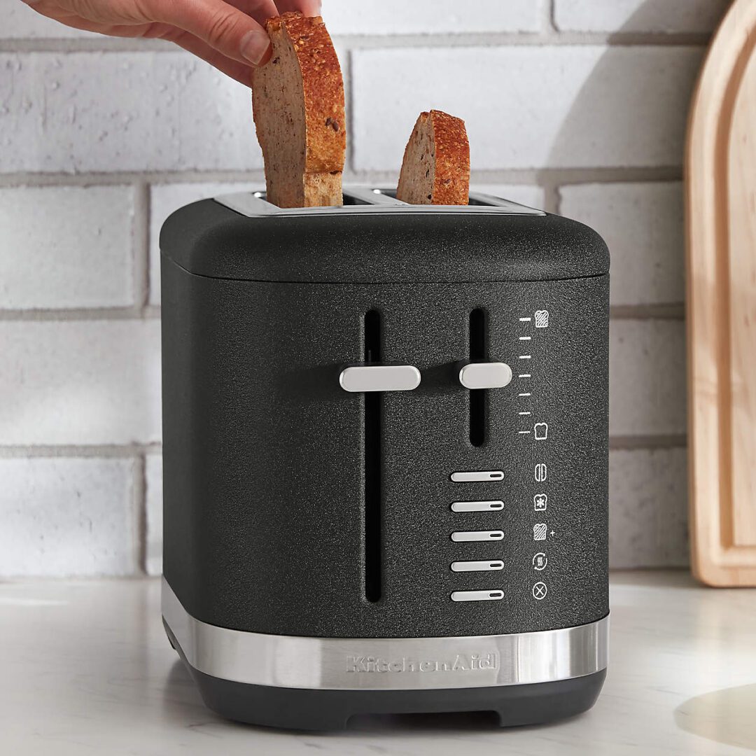 A modern black toaster with bread slices inside on a kitchen counter.
