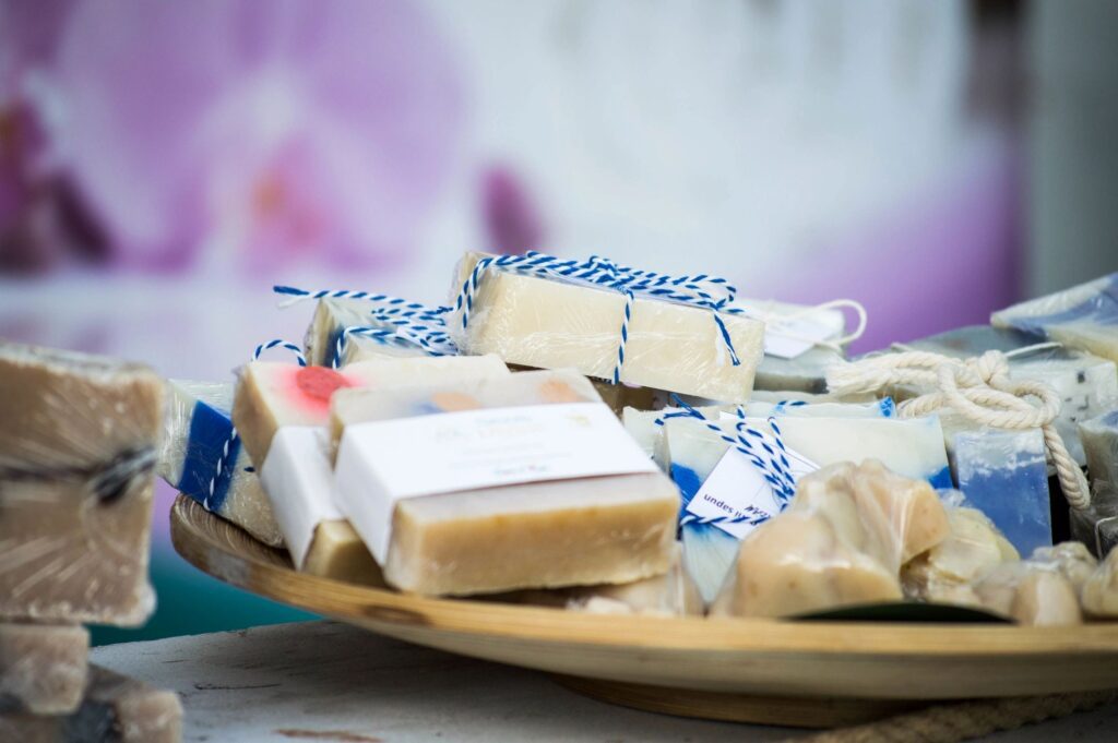A stack of handmade soap bars wrapped in decorative paper on a wooden plate.