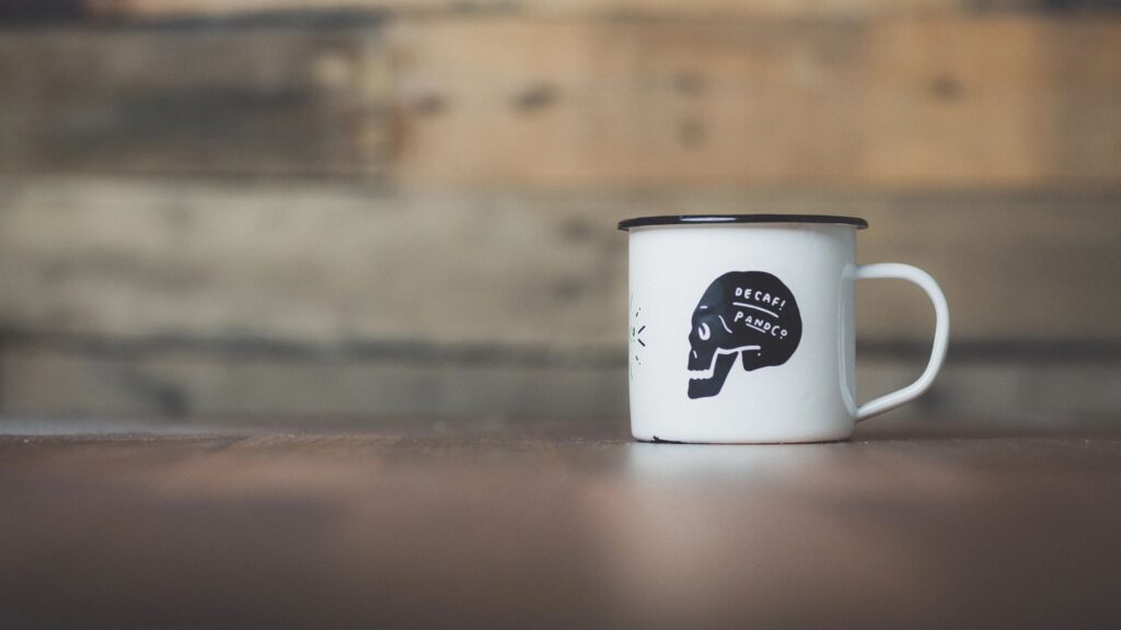 White enamel mug with a black brain graphic and text on a wooden surface.
