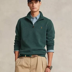 Man wearing a dark green quarter-zip sweater and beige pants.